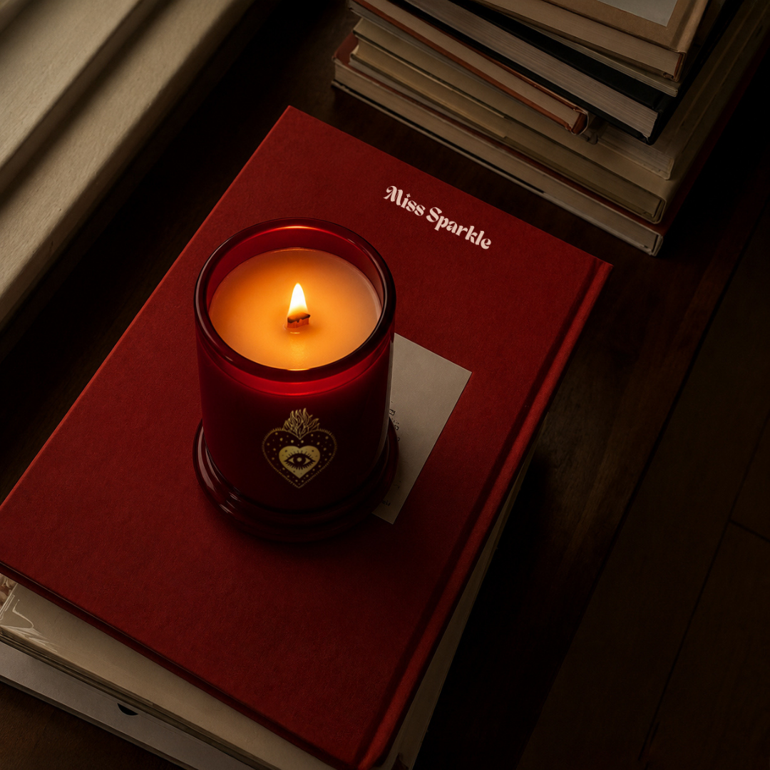 Lit Miss Sparkle candle resting on a red book